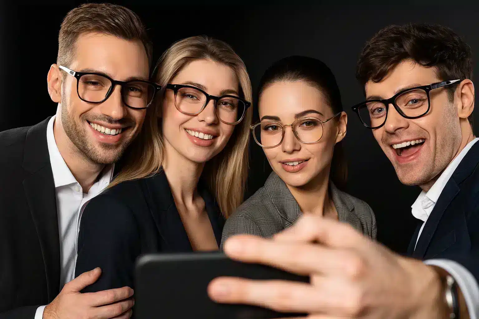 Vier Kollegen machen ein Selfie mit Smartphone bei einer Firmenveranstaltung